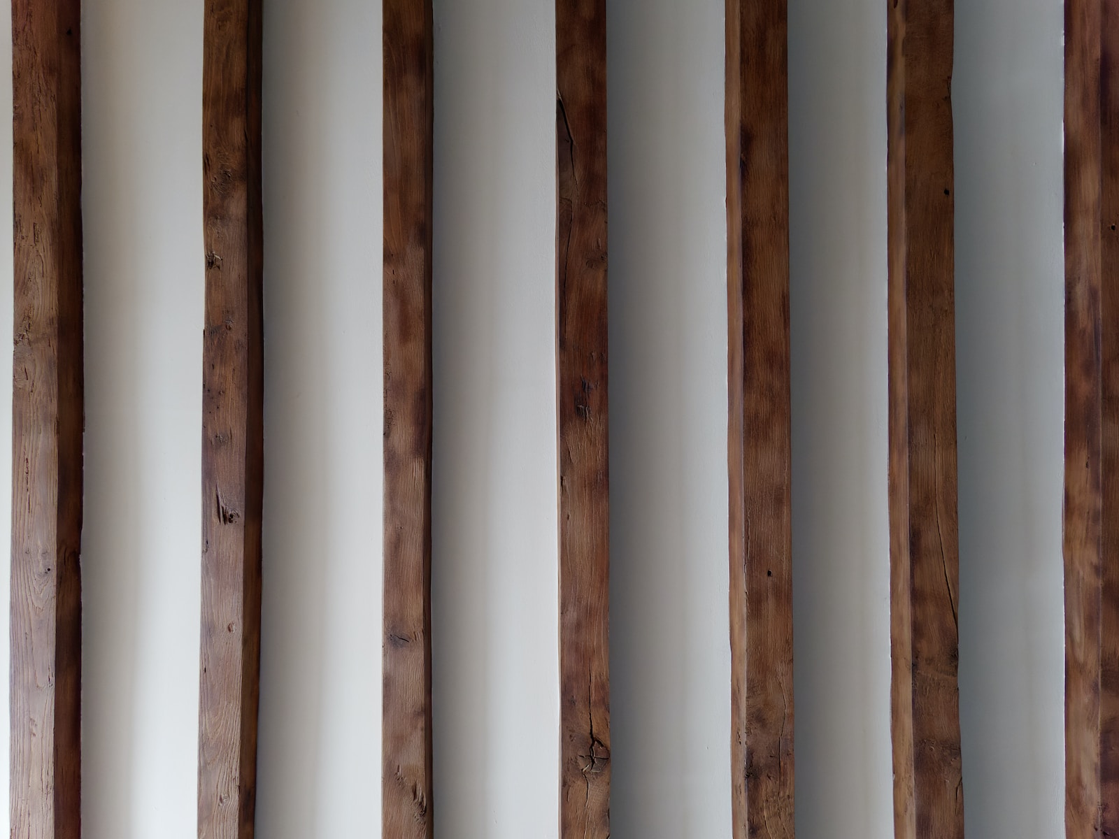 a row of wooden poles against a white wall